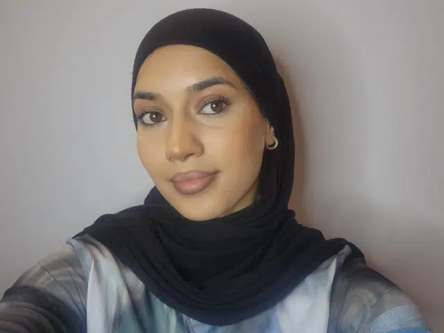 A young South Asian women wearing a black head scarf - looking ahead