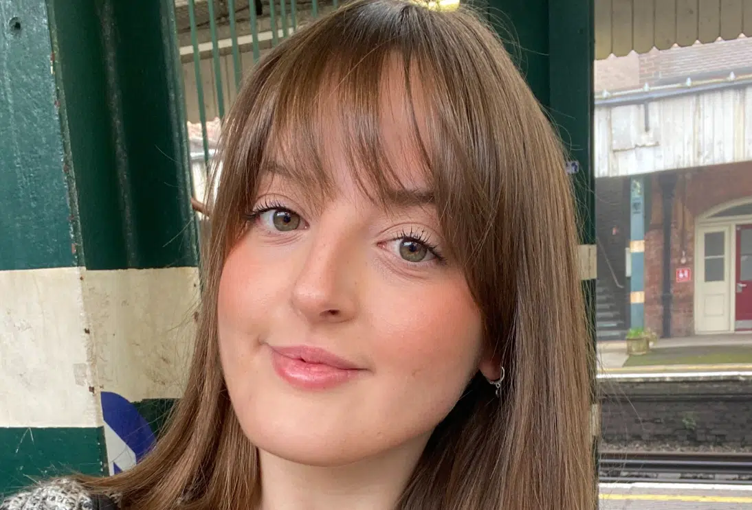 A young white women with long brown hair and a fringe looking ahead.